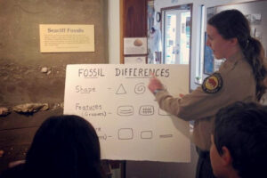 An interpreter is presenting to a group of students at Seaclliff State Beach