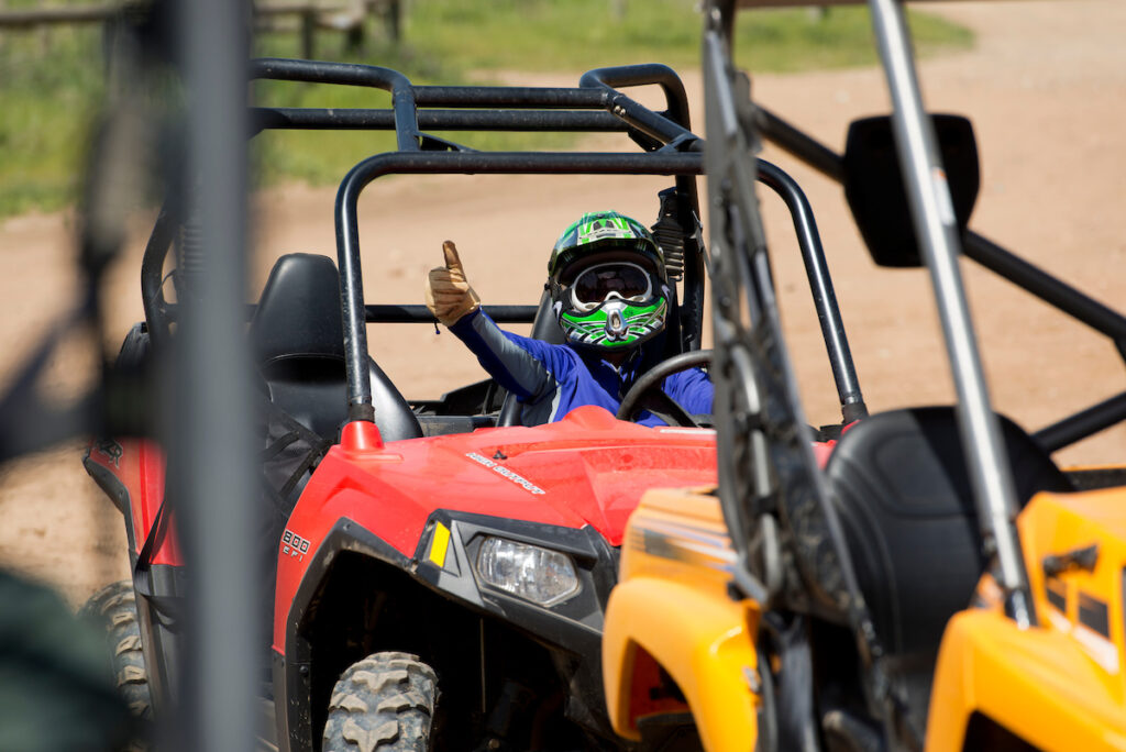 Photo of or from Prairie City State Vehicular Recreation Area. A person is sitting in an ROV wearing a helmet, giving a thumbs up