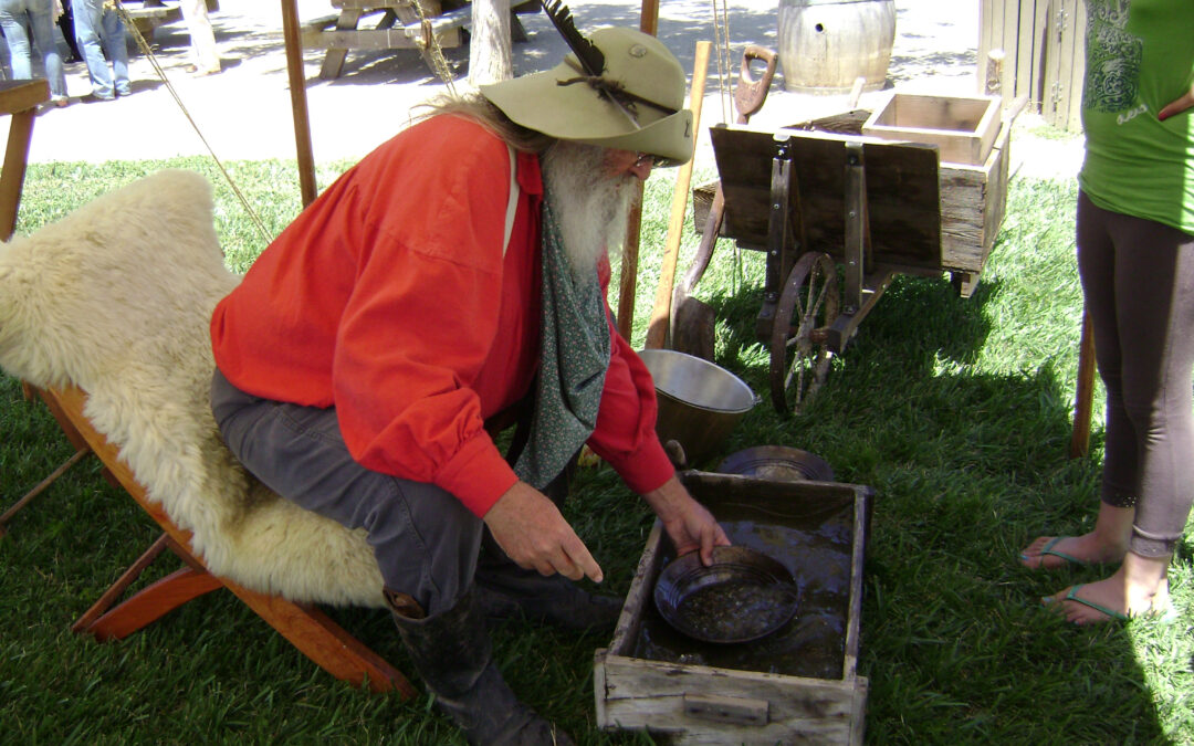 A living history volunteer in historic costume demonstrates gold panning