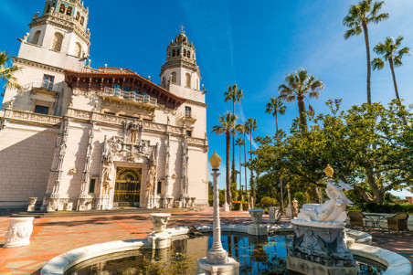 A view of the exterior of Hearst Castle. There's a fountain in the foreground, and the entrance of Hearst Castle