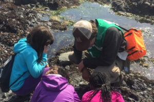 A guide is talking about tidepools to a group of school children