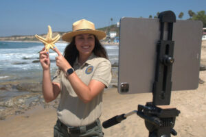 An interpreter is holding a sea star during a virtual PORTS presentation