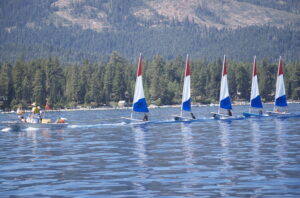 A sailing class on Lake Tahoe - 5 small sailboats with red, white, and blue sails are lined up.