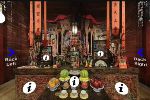 The interior of an Chinese temple. There are food offerings on an altar, incense, and many pieces of art on the altar.