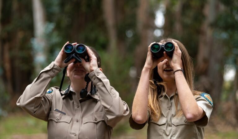 Two interpreters are looking through binoculars