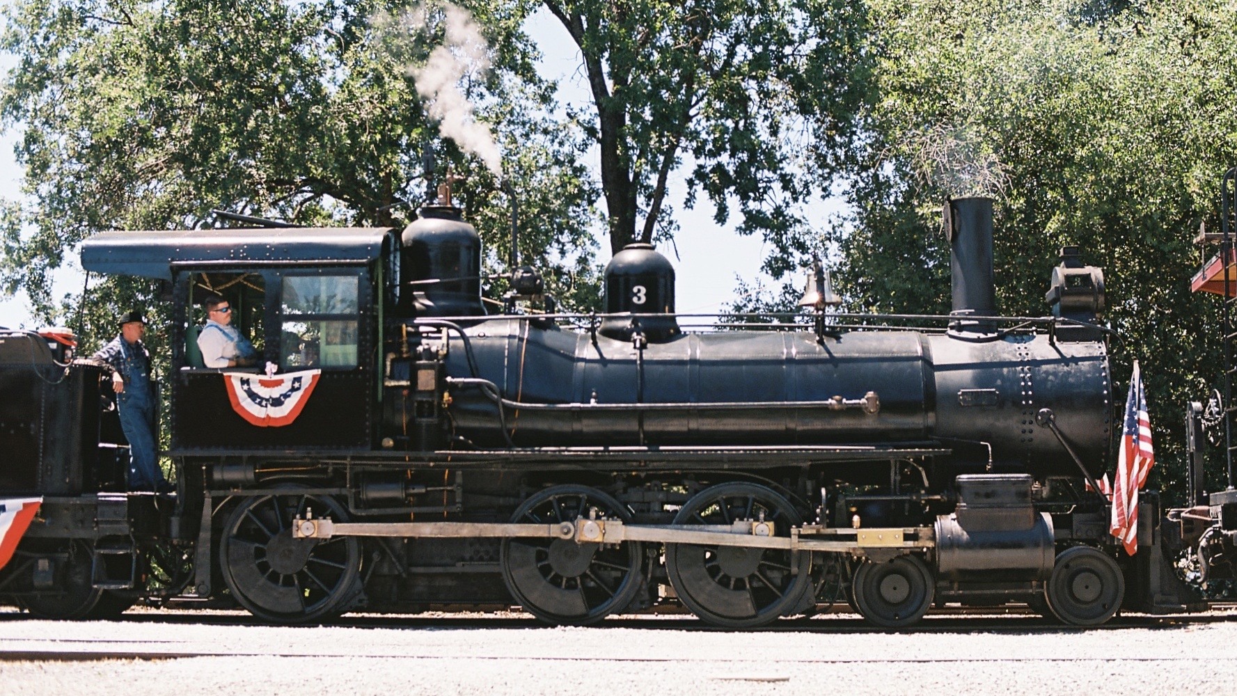 Photograph of steam locomotive, Sierra Railway No. 3, under steam and wearing American flags and bunting at Railtown 1897 State Historic Park
