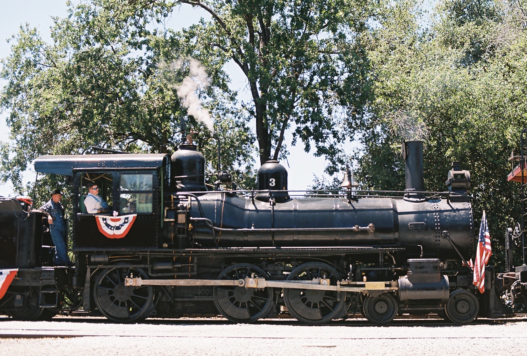 Photograph of steam locomotive, Sierra Railway No. 3, under steam and wearing American flags and bunting at Railtown 1897 State Historic Park