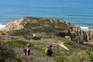 A group of hikers hike along a coastal trail in Torrey Pines State Natural Reserve